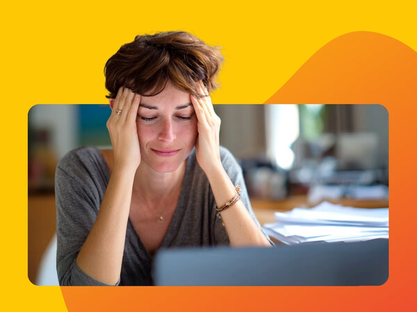 Eine Frau sitzt angespannt vor einem Laptop, Kopf auf den Händen abgestützt, versucht sich zu konzentrieren