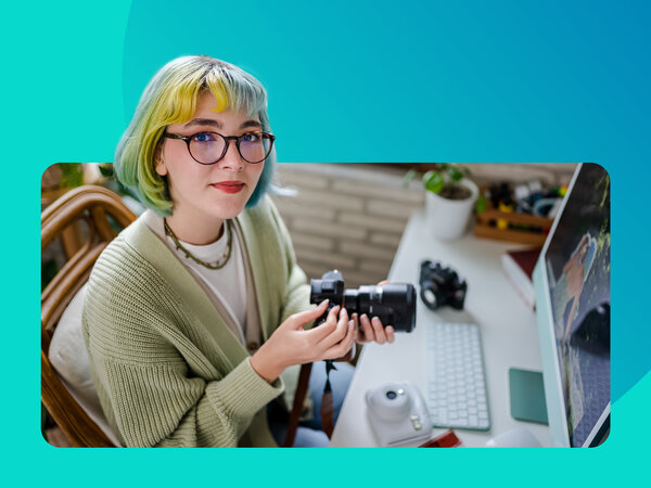 Frau mit Brille und Kamera am Laptop.