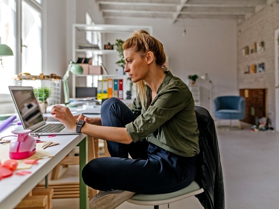 Eine Frau arbeitet am Laptop in einem kreativen Büroraum.