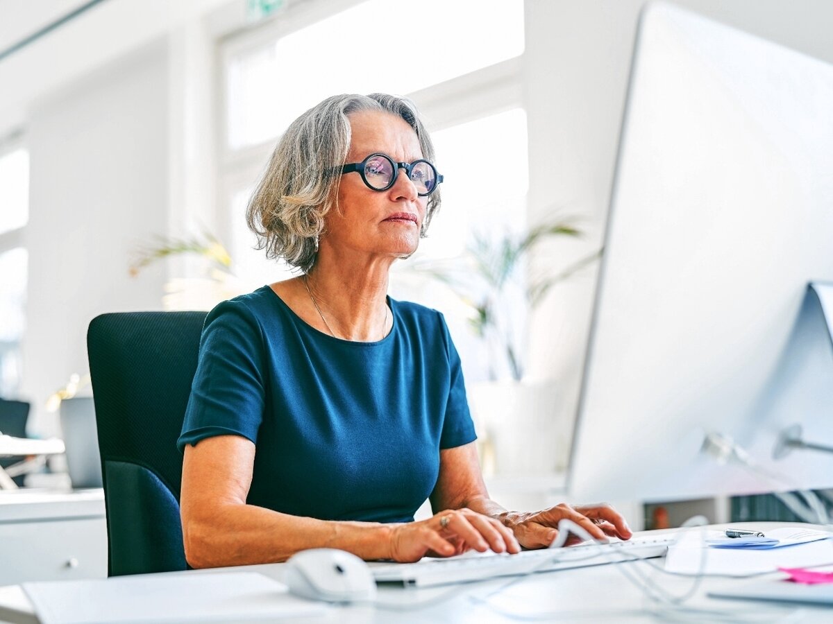 Frau im mittleren Alter am Computer. Eine Frau im mittleren Alter bei der Arbeit vor einem Computerbildschirm.