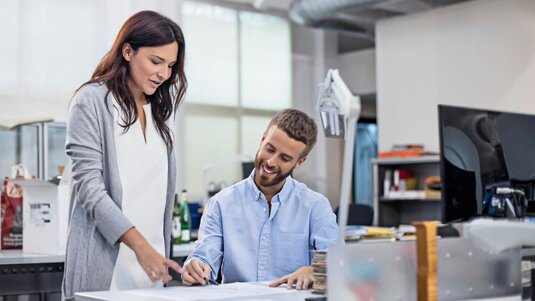 Eine Frau und ein Mann im Büro besprechen eine technische Planzeichnung