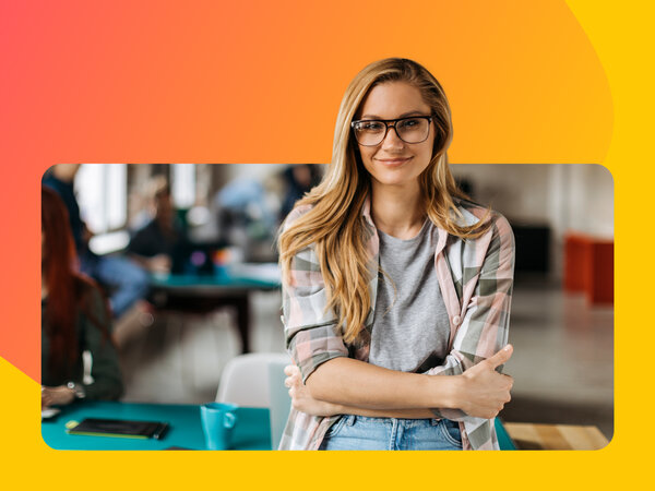 Frau mit Brille steht lächelnd und mit verschränktem Arm in Schulungsraum.