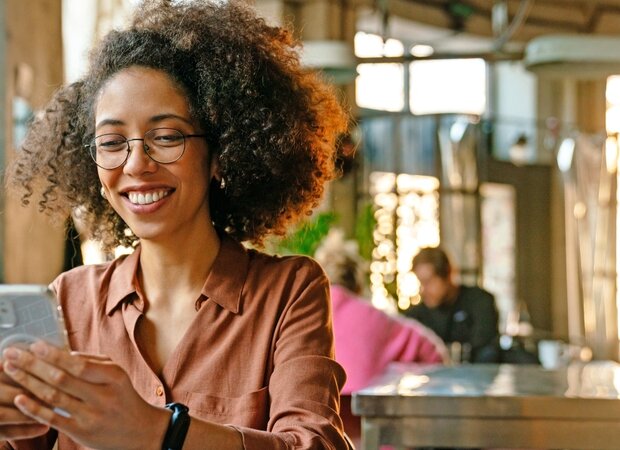 Eine Frau im Café mit ihrem Smartphone in der Hand.